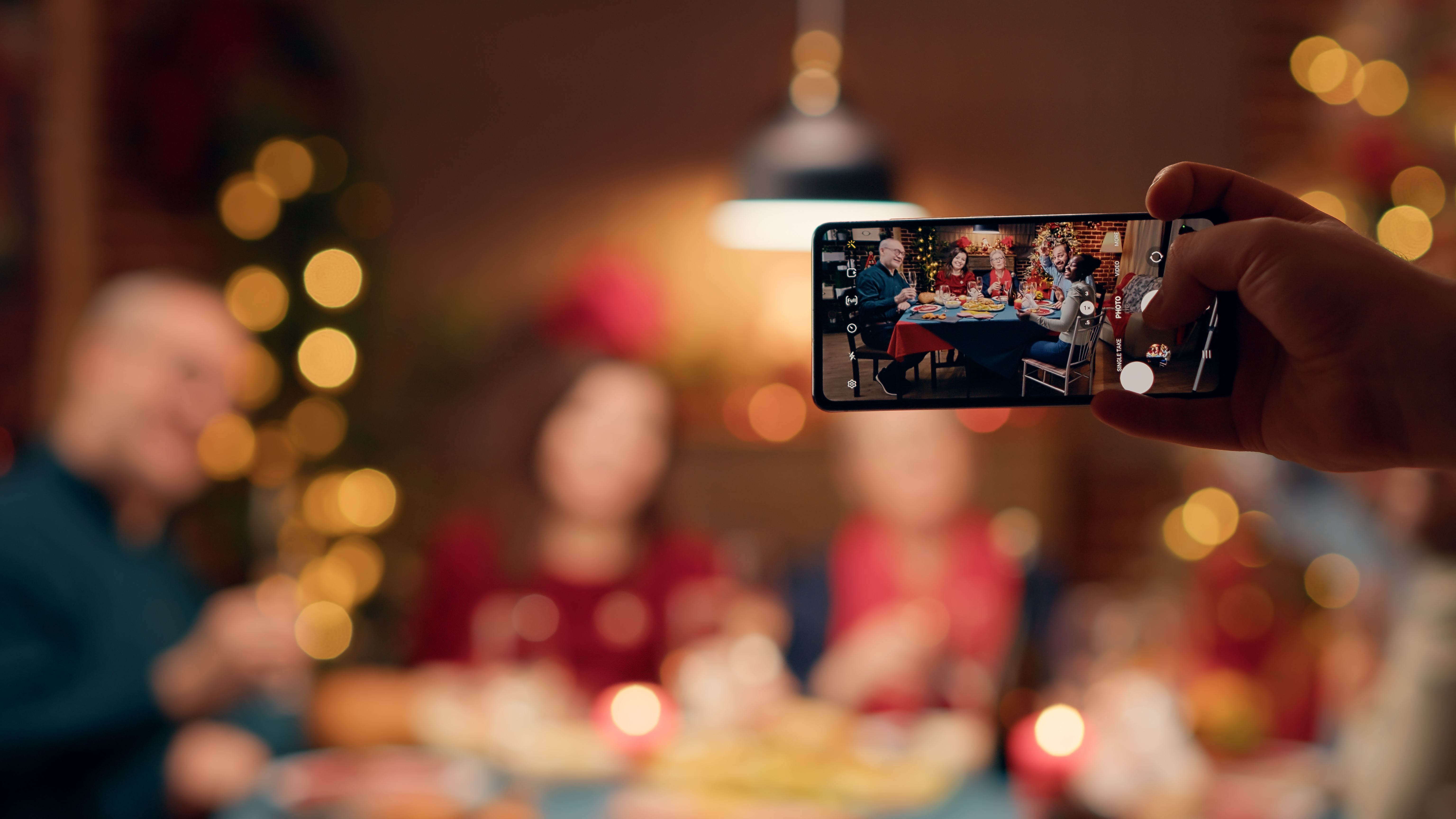 festive-family-members-getting-photographed-with-smartphone-while-sitting-table-enjoying-christmas-dinner-together-person-taking-photo-happy-people-celebrating-winter-holiday-with-phone-device